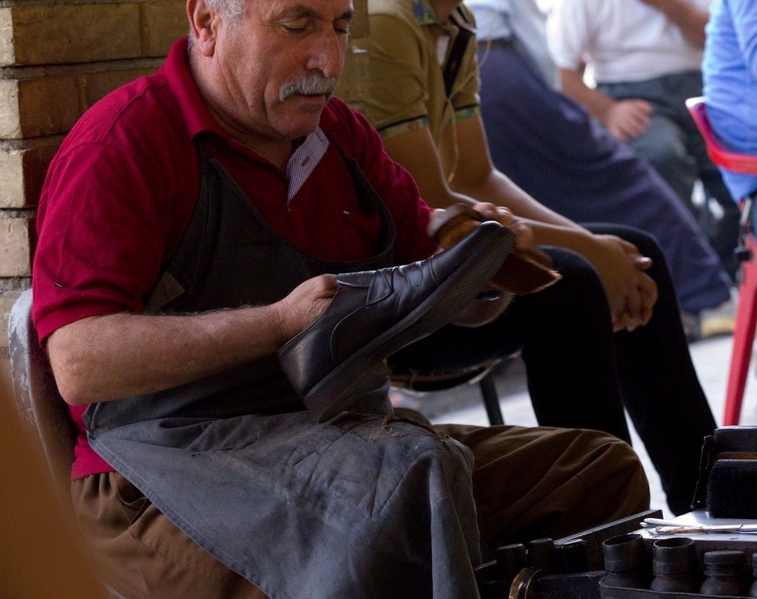 Skomakare bearbetar en lädersko med verktyg i en verkstad